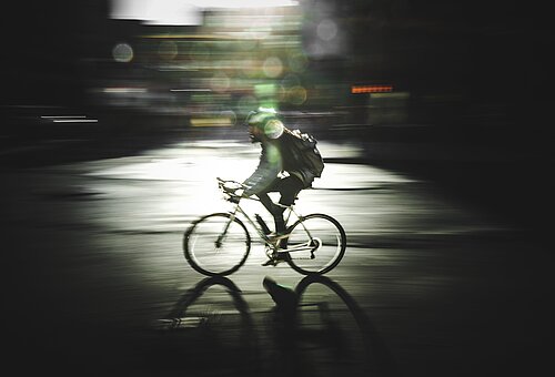 Fahrradfahrer liefert vor einem dunklen Hintergrund Waren auf Juist aus