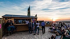 Sonnenuntergang im Sommer am Juister Strand in der Strandbar mit Sitzen und Liegen und Drinks