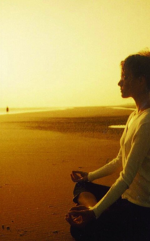 Person meditiert auf Juist bei der gesundheitswoche am Strand