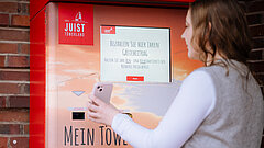 Tourist-Information im Rathaus auf Juist - Bild zeigt eine Kundin am Gästebeitragsautomaten an der Tourist-Information am Rathaus auf Juist bei der Zahlung ihres Gästebeitrags
