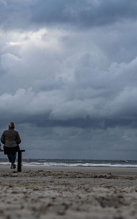 Zwei Personen sitzen auf einer Bank am Strand auf Juist