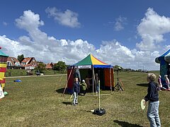 Bild zeigt Kinderprogramm beim Juistival - Musikfestival auf Juist - auf der Wiese zwischen Deich und Hafen mit verschiedenen bunten Attraktionen und Kindern in Action