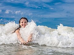 Junge Frau schwimmt in einer Wellt auf Juist in der Nordsee
