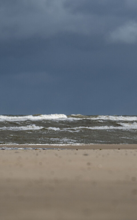 Person im Regenmantel auf Juist am Strand