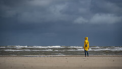 Person im Regenmantel am Strand auf Juist