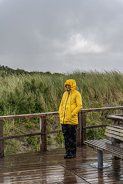 Herbsturlaub auf Juist - Frau in einer gelben Regenjacke bei Sonnenschein auf Juist im Herbst