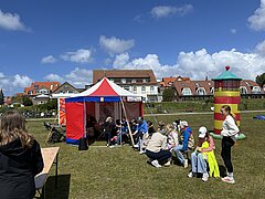 Bild zeigt Kinderprogramm beim Juistival - Musikfestival auf Juist - auf der Wiese zwischen Deich und Hafen mit verschiedenen bunten Attraktionen und Kindern in Action