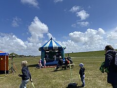 Bild zeigt Kinderprogramm beim Juistival - Musikfestival auf Juist - auf der Wiese zwischen Deich und Hafen mit verschiedenen bunten Attraktionen und Kindern in Action
