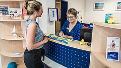 Beratung Gast am Counter in der Tourist-Information im Rathaus auf Juist