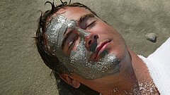 Gesichtsanwendung bei einem Mann auf Juist am Strand