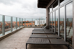 Panorama Sauna auf Juist - Bild zeigt den Außenbereich auf der Terrasse mit Liegen udn Fensterfront