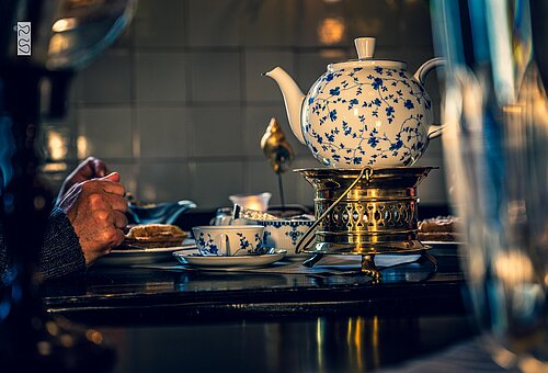 Teekanne mit ostfriesischem Rosenmuster auf einem Stövchen in einem Teehaus auf Juist
