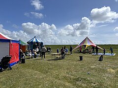 Bild zeigt Kinderprogramm beim Juistival - Musikfestival auf Juist - auf der Wiese zwischen Deich und Hafen mit verschiedenen bunten Attraktionen und Kindern in Action