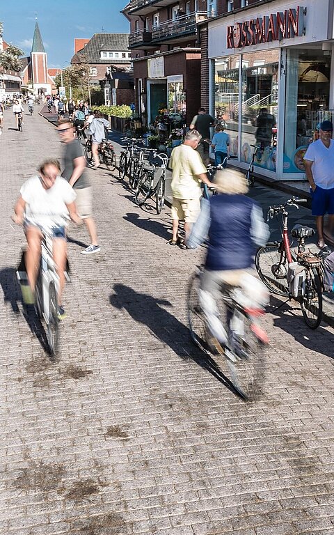 Vogelperspektive auf die Wilhelmstraße auf Juist mit zahlreichen Passanten und einigen Geschäften und Lebensmittelläden