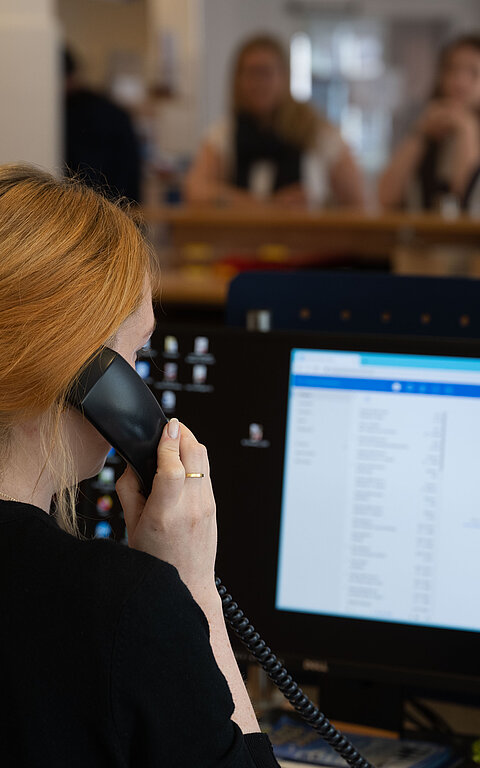 Beratung am Telefon mit Frau am Telefon und Display in der Tourist-Information im Rathaus auf Juist
