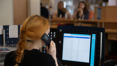 Beratung am Telefon mit Frau am Telefon und Display in der Tourist-Information im Rathaus auf Juist