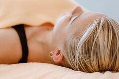 Wellnessangebote auf Juist - Foto zeigt eine blonde Frau schräg von hinten, die in ein HAndtuch gehüllt auf einer Behandlungsliege liegt