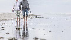 Spaziergang Paar am Juister Strand direkt an der Wasserkante des Reizklimas bei einer Kur auf Juist