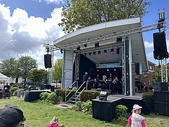 Bild zeigt Stimmung auf dem Kurplatz auf Juist beim Juistival feiernden Menschen mit Sicht auf die Bühne bei einem Konzert