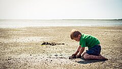 Junge spielt im Wattenmeer auf Juist
