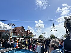 Bild zeigt Stimmung auf dem Kurplatz auf Juist beim Juistival feiernden Menschen mit Sicht über den Schiffchenteich
