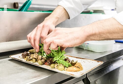 Eine Person richtet Essen in einer Küche auf Juist an