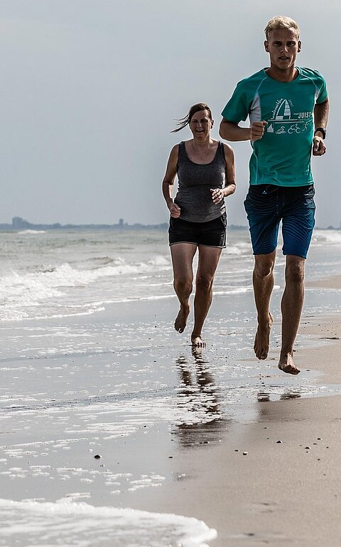 Zwei Menschen joggen auf Juist am Strand